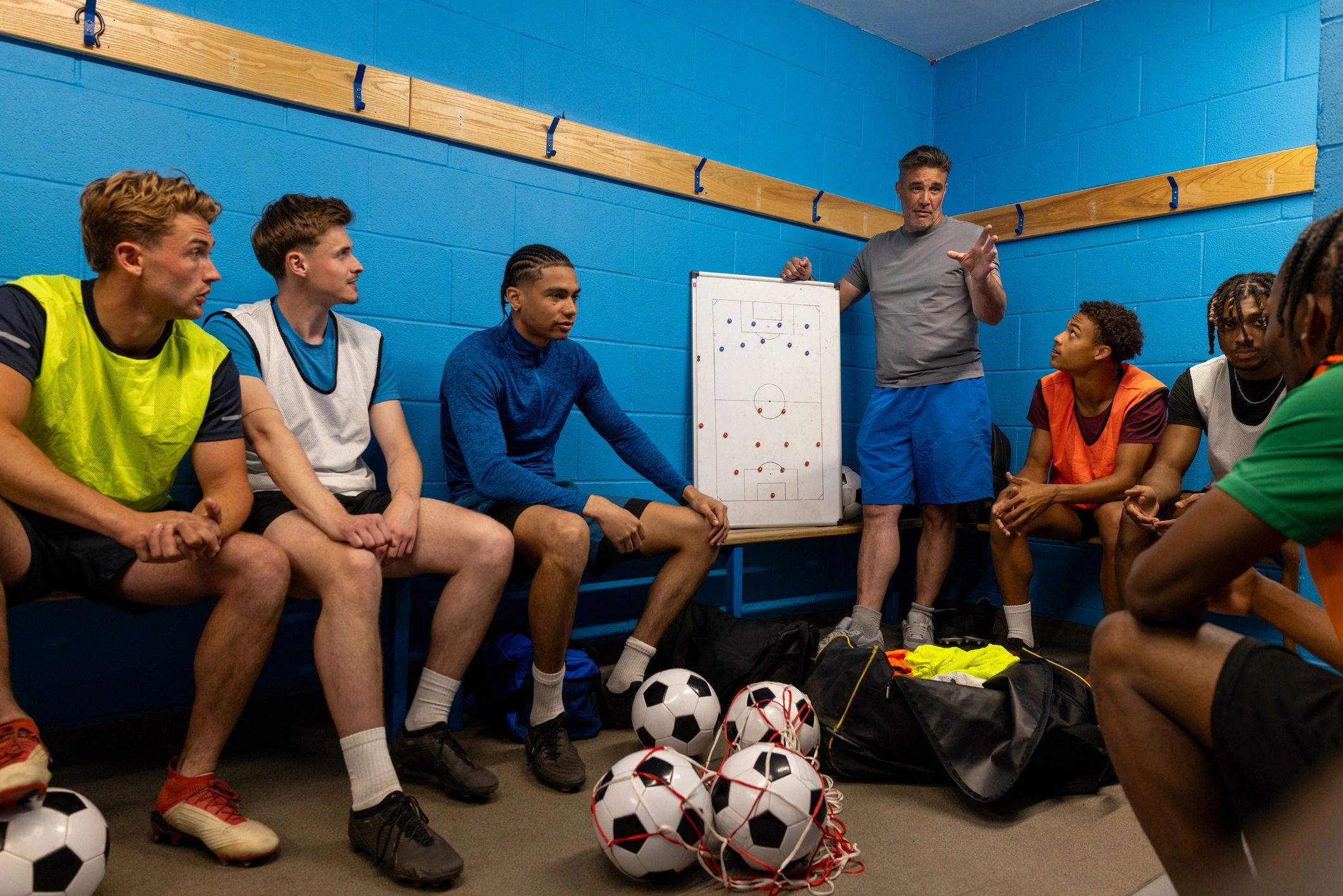 Athletes and coach reviewing game strategy in the locker room